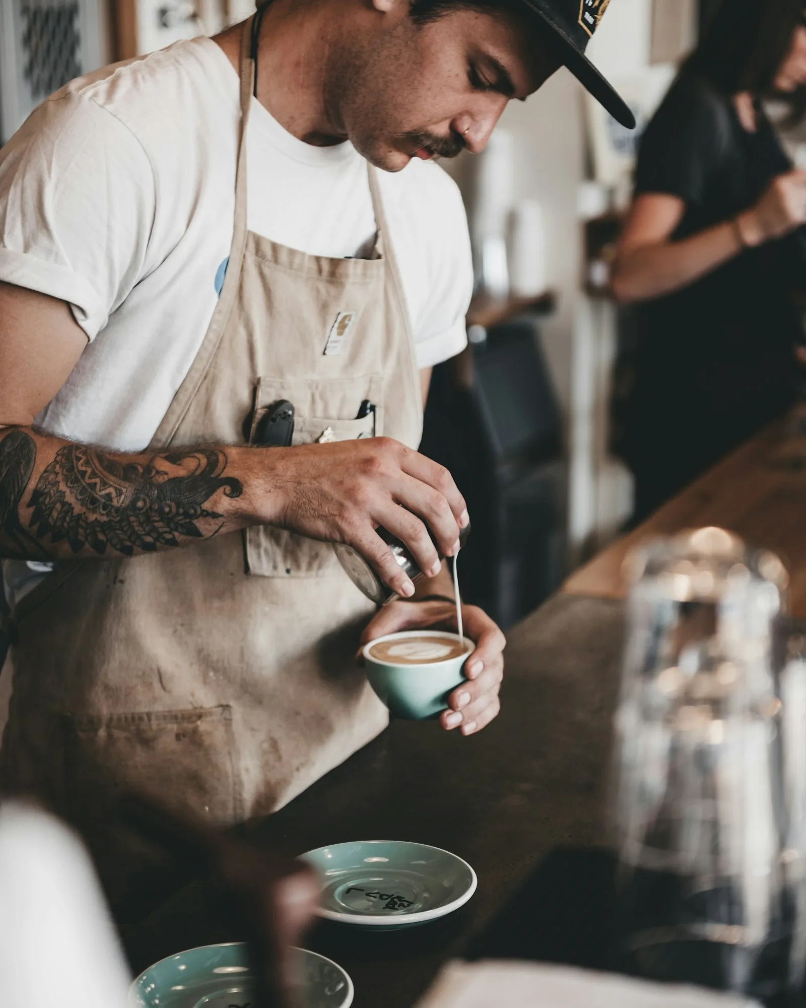 A barista pouring latte art behind the counter