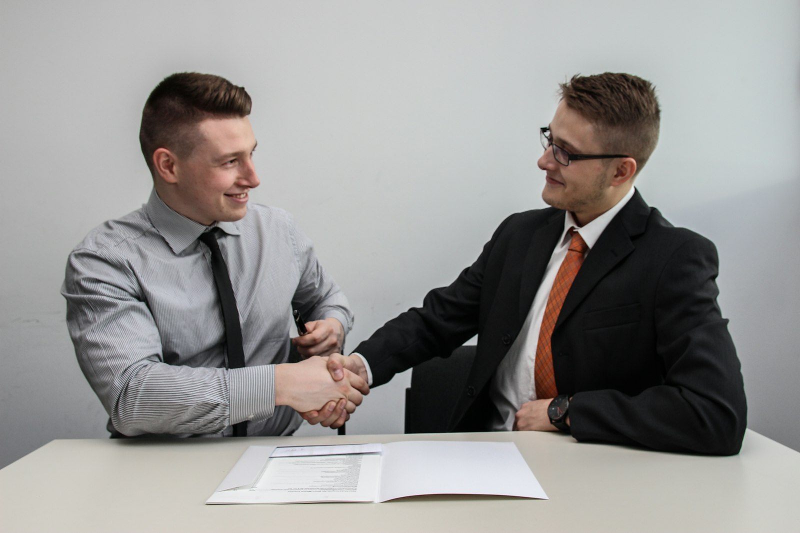 Two people shaking hands across a desk
