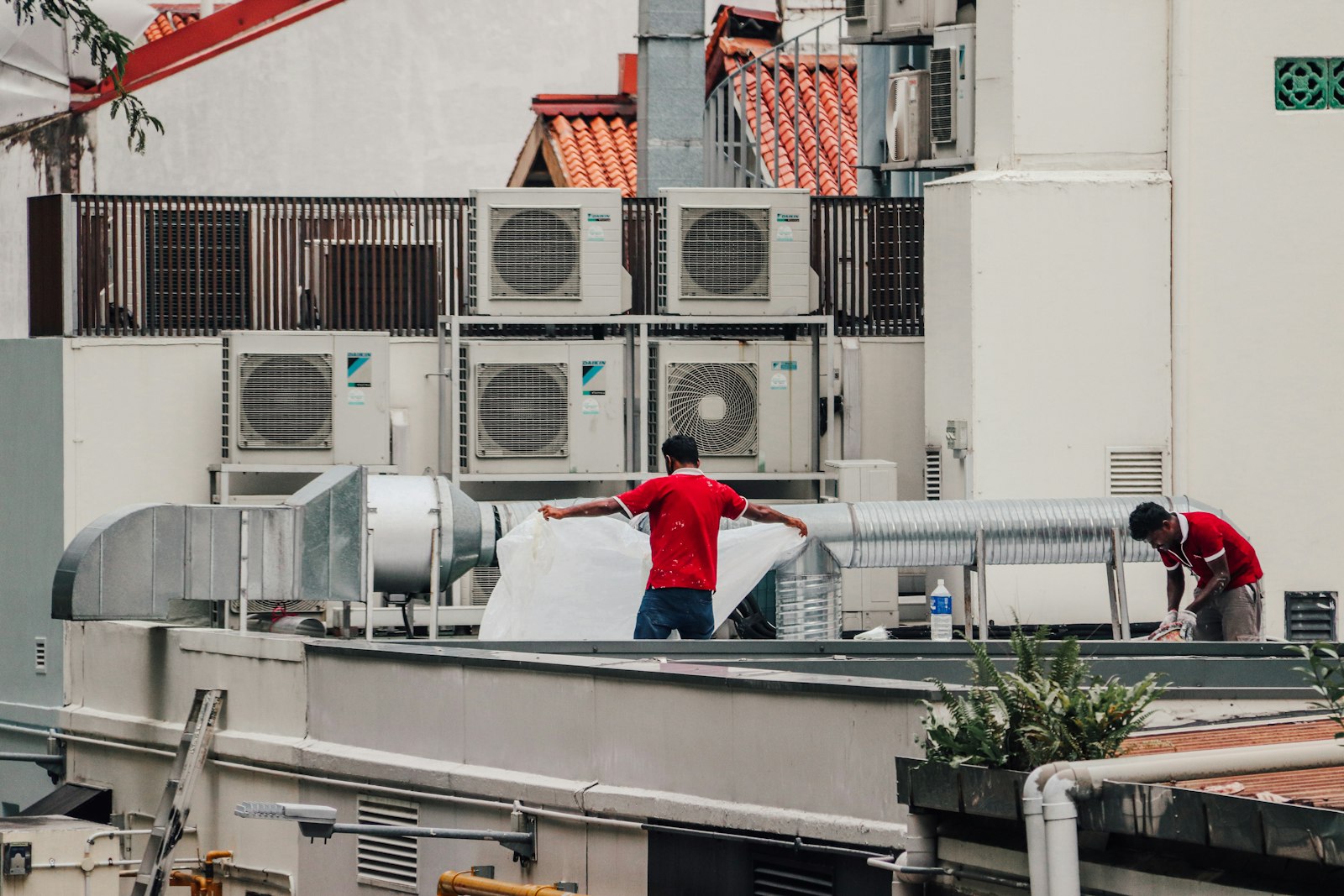 Two HVAC technicians working on a rooftop unit